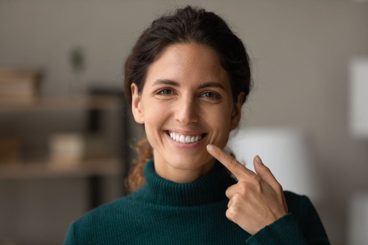 Shiny smile. Portrait of young happy hispanic woman satisfied patient of dental clinic. Millennial lady enjoy perfect result of orthodontic care procedures look at camera point on white straight teeth