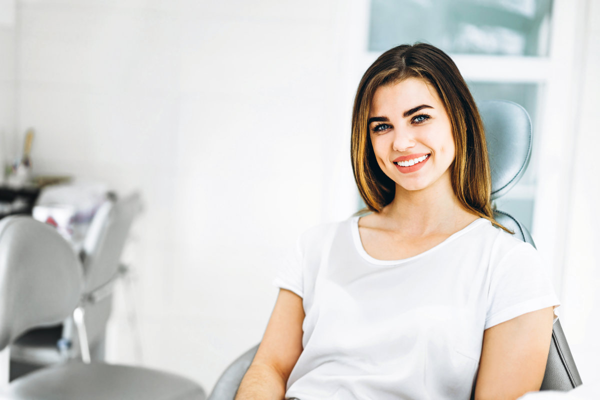 Pretty happy and smiling dental patient sitting in the dental chair at the dental office