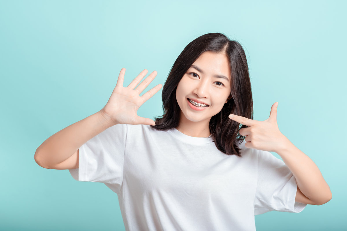 Dental braces of young asian woman wearing braces beauty smile with white teeth increase confidence for healthy on blue background isolated studio shot, Happiness teenager smiling facial expression.