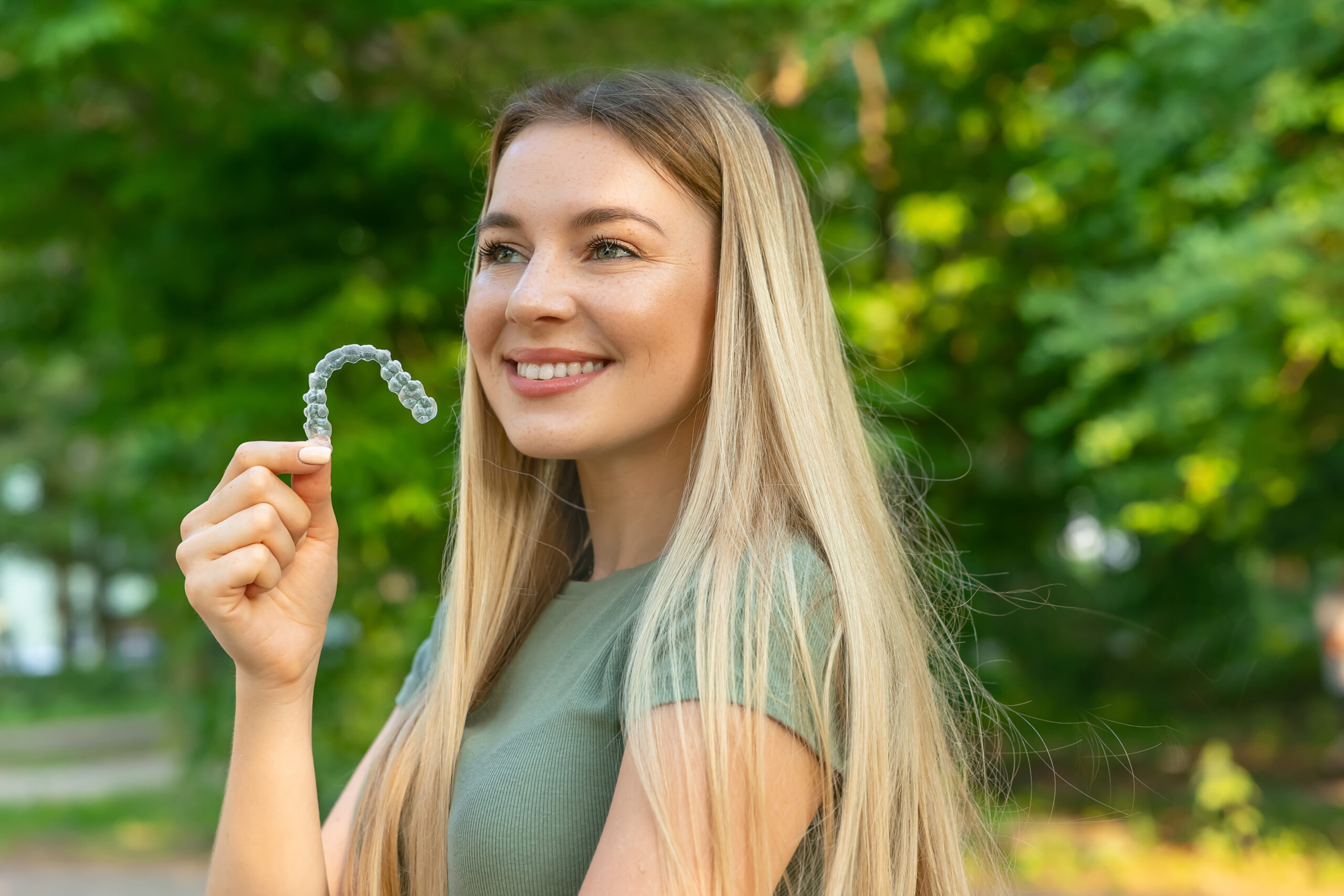 Smiling woman with perfect and healthy teeth using removable braces or aligner for straightening and whitening teeth. Orthodontic treatment for correction of bite.